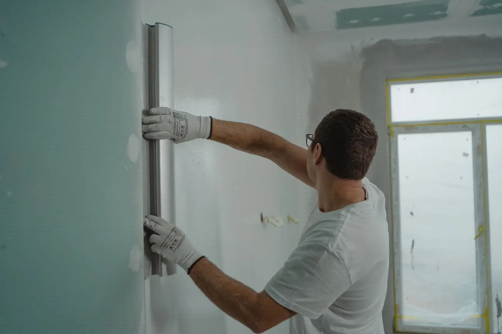 Artisan lissant un mur de plâtre dans une pièce claire